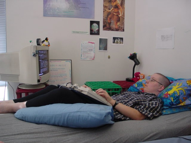 1998: a person lying on a futon with a keyboard on a lap tray, and a CRT monitor on a ledge beside them