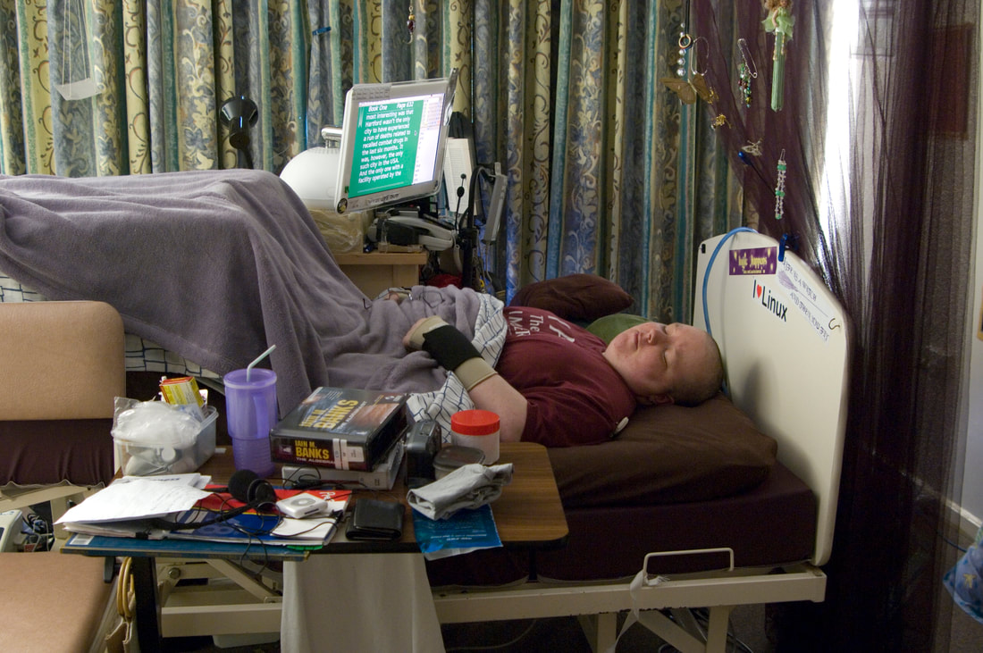 2007: a person lying in an adjustable bed, with a large wooden kitchen island beside it holding a computer and other items