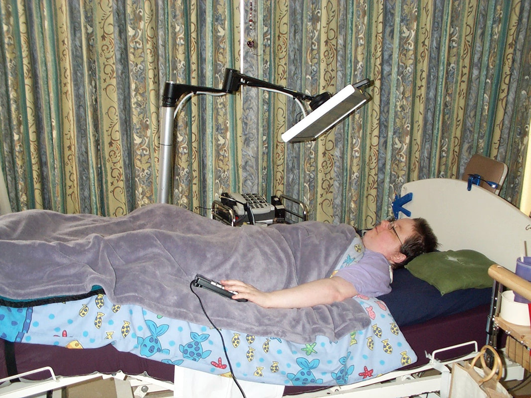 2008: a person lying in an adjustable bed under a blanket, with a monitor and a lamp on jointed metal arms above them